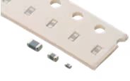 Several small, rectangular surface-mount devices placed next to a white mounting strip with three holes.