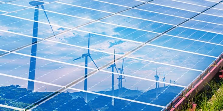 A close-up view of solar panels reflecting the sky and several wind turbines.