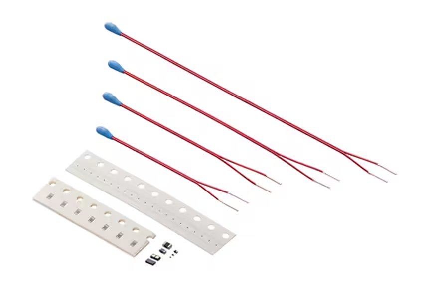 A selection of electronic components is displayed, including four blue-tipped devices with long red wire leads and several small black and silver components.
