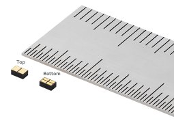 The image shows a metallic precision ruler with clear measurement markings, accompanied by two small electronic chips labeled 'Top' and 'Bottom.'