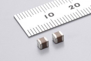 Two small rectangular electronic components are placed on a light surface next to a white metric ruler. 