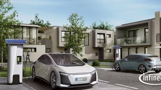 Two modern electric vehicles are parked and charging at solar-powered charging stations in a contemporary suburban neighborhood. The Infineon logo is visible in the lower right corner.