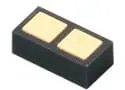 A close-up of a small, rectangular electronic component with two gold-colored contact pads on its top surface.