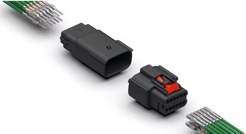 Two black electrical connectors with multiple green wires attached. The connectors are separated, displaying their pin configurations and a visible red locking mechanism on one connector.