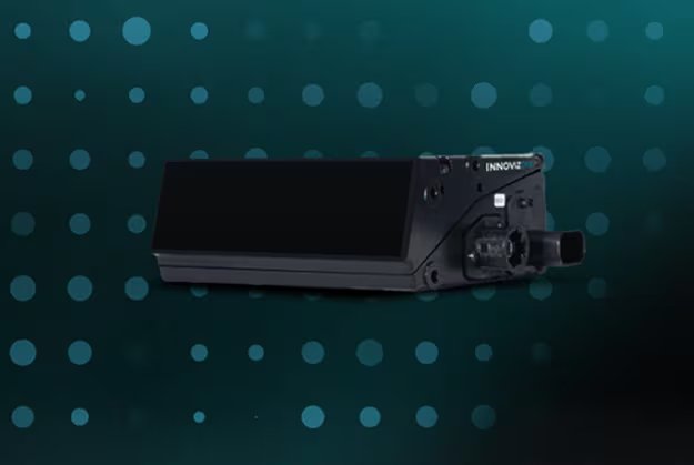 A black electronic device labeled 'INNOVIZ' is displayed prominently against a teal background with circular dot patterns. The device features a rectangular screen and several ports or connectors on its side.