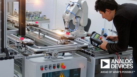 An engineer is seen working with a robotic arm in a modern industrial environment. The workspace features advanced machinery, control panels, and automated systems. The engineer is using a handheld device to interact with the equipment.