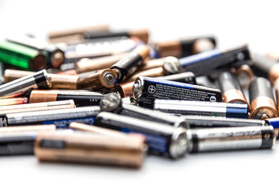A collection of various batteries, including AA and AAA sizes, scattered on a white surface.