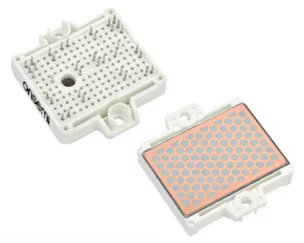 Full SiC module in F2 packaging: The image shows two rectangular electronic components, one displaying a grid of metallic pins and the other featuring a grid of circular copper-colored contacts. Both components are white with mounting holes.