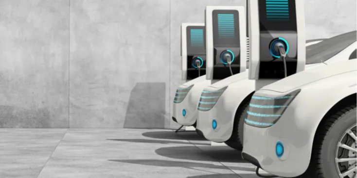 Three modern white electric vehicles are parked side by side, each connected to a sleek charging station.