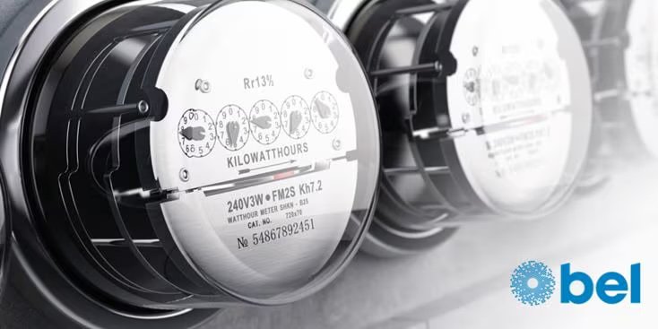 A detailed view of an electric meter showing its numeric dials and technical specifications. The lower right corner displays the 'bel' logo in blue.