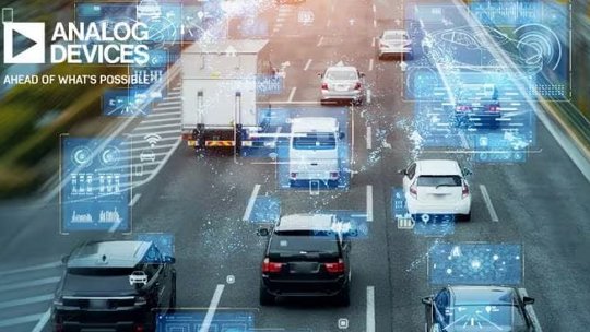 A multi-lane highway scene features several cars and a truck, overlaid with digital interface graphics representing smart vehicle technology. The Analog Devices logo and the phrase 'AHEAD OF WHAT'S POSSIBLE' are clearly visible in the upper left corner.