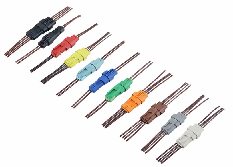 Image of multiple inline electrical wire connectors arranged in a diagonal row. Each connector is attached to paired copper wires and presented on a white background. The connectors come in various solid colors including black, red, yellow, green, blue, orange, brown, gray, and white. The clean layout highlights the variety and organization of the wiring accessories.