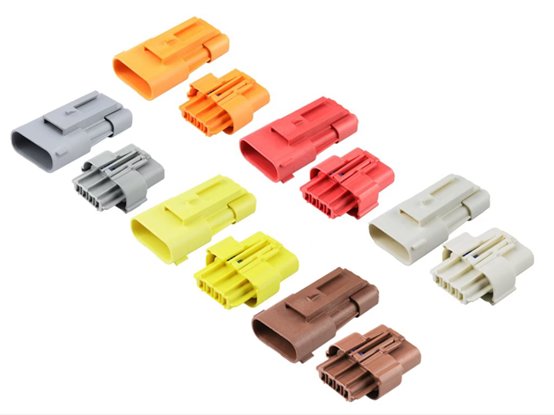 Image of multiple plastic electrical connectors arranged on a white background. The connectors are shown in various colors including gray, yellow, red, brown, and off-white. Each connector features different pin configurations and housing shapes, suggesting compatibility with various wiring applications. The clean layout highlights the design details and color-coded organization of the components.