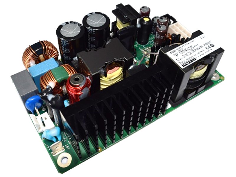 The image shows a close-up of an electronic power supply circuit board featuring various components such as capacitors, coils, and heat sinks. The board is photographed against a white background, highlighting its intricate details and layout. Visible numeric values and technical markings are present on some parts, but no specific brand or model is clearly identifiable. The overall mood is technical and utilitarian, with a palette dominated by metallic and electronic hues.