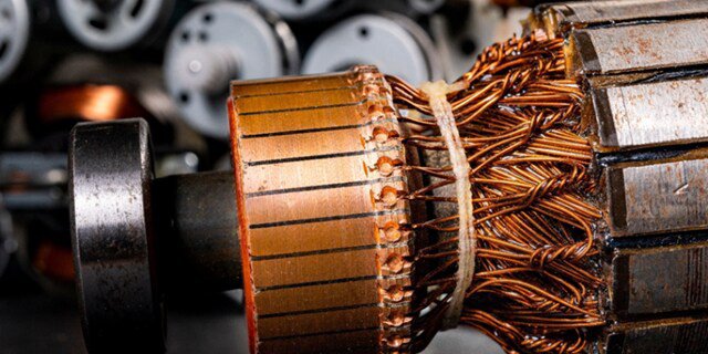 A detailed view of an electric motor rotor showcases tightly wound copper wires and metallic components. The image highlights the intricate construction of the rotor, with other motor parts visible in the blurred background.