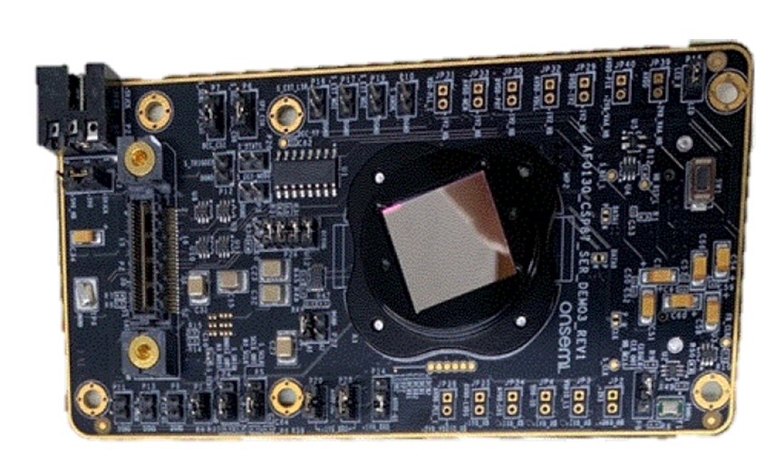 Close-up view of an electronic circuit board featuring a large central sensor or processor chip. The board is populated with numerous small components, connectors, and gold mounting holes around the edges. Fine printed circuitry and component labels are visible across the dark substrate. The image is isolated on a white background, emphasizing the technical details of the hardware.