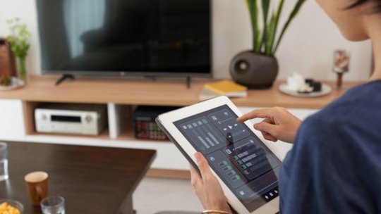 Image of woman controlling home security system on smart device