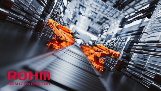 A technician or engineer leans over a long piece of industrial equipment in a bright, modern laboratory or manufacturing facility. 