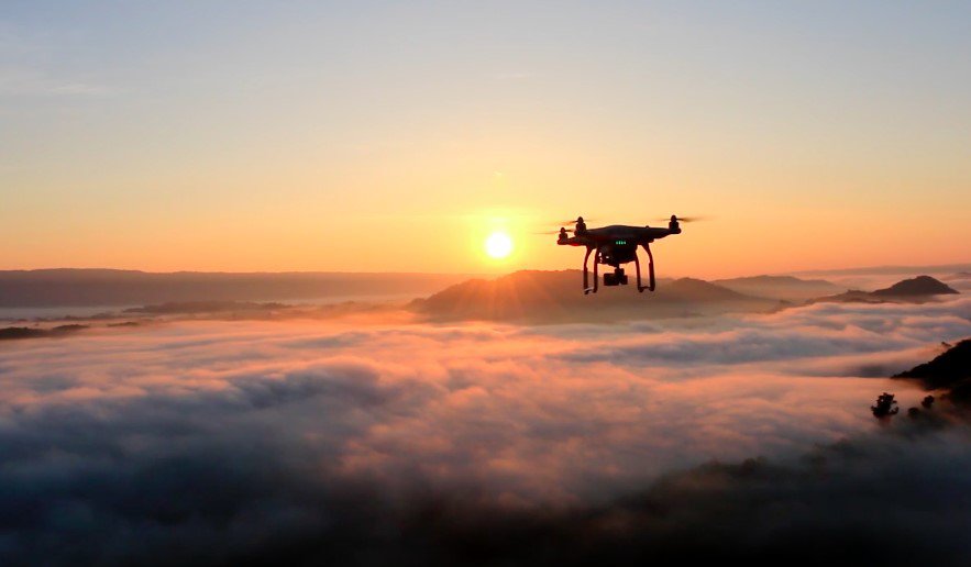 Image of drone flying above clouds at sunrise