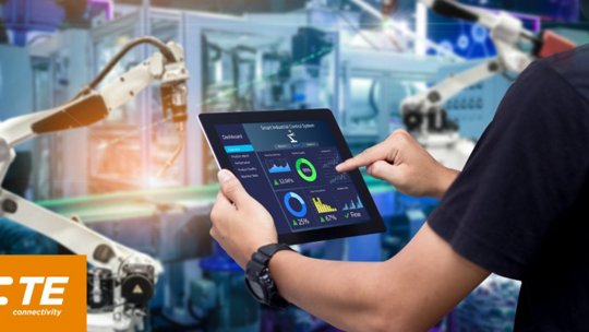 산업 환경에서 로봇 팔을 작업하며 스마트 기기를 사용하는 사람의 이미지