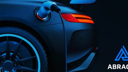 A sleek electric car is shown in close-up while connected to a charging station.