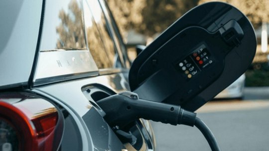 Primo piano di un veicolo elettrico collegato a una stazione di ricarica in un ambiente esterno