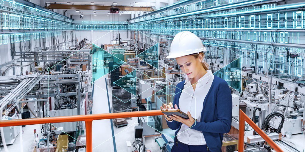 一名身穿正装、戴着白色安全帽的人使用平板电脑监控高科技自动化工厂的运作。