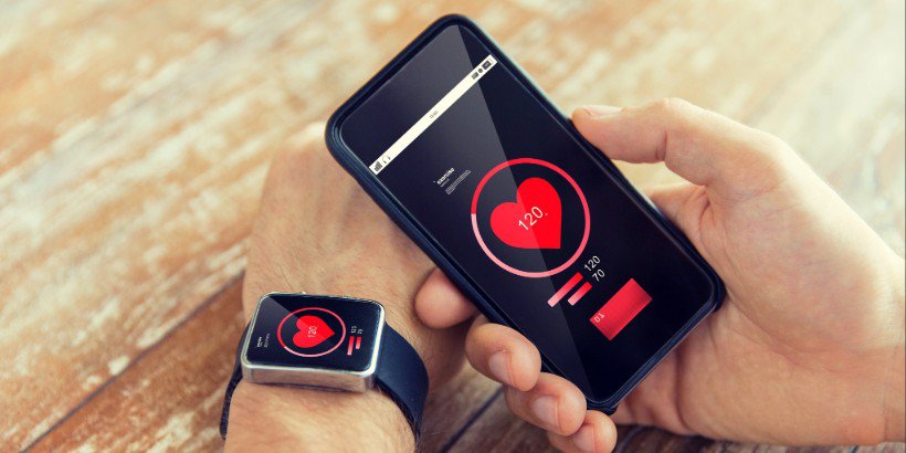 A close-up of a smartwatch and smartphone displaying heart rate data.