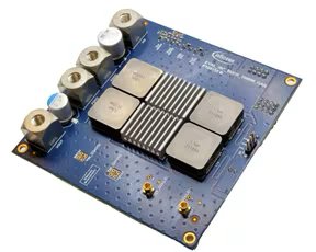 A blue printed circuit board features multiple metallic heat sinks and several cylindrical connectors along one edge. The board displays intricate circuitry and gold contact points, with visible text including 'Analog Devices' and 'ADP1055'.