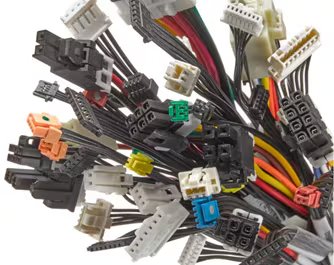 A bundle of various computer power supply cable connectors is shown in close-up. The image features multiple colored wires and different connector types, including black, white, orange, green, and blue plastic housings. The connectors are tightly grouped, highlighting the complexity and variety of modern computer hardware wiring.