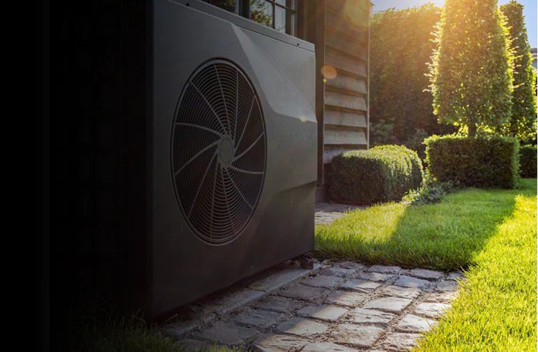 A modern outdoor heat pump unit is installed beside a house, partially shaded by the building.