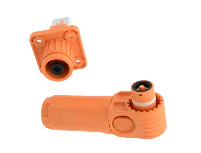 An orange industrial electrical connector and matching socket. Both components feature ribbed grips and cylindrical shapes, designed for secure electrical connections. The connector has a locking mechanism and the socket is mounted on a square flange.