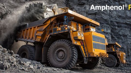 Un enorme camión volquete amarillo de minería es capturado descargando rocas en un entorno de cantera agreste.
