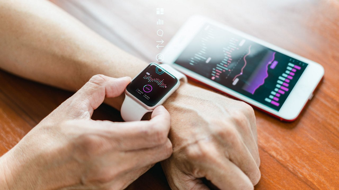 A person interacts with a smartwatch displaying health tracking data, paired with a smartphone showing detailed graphs.