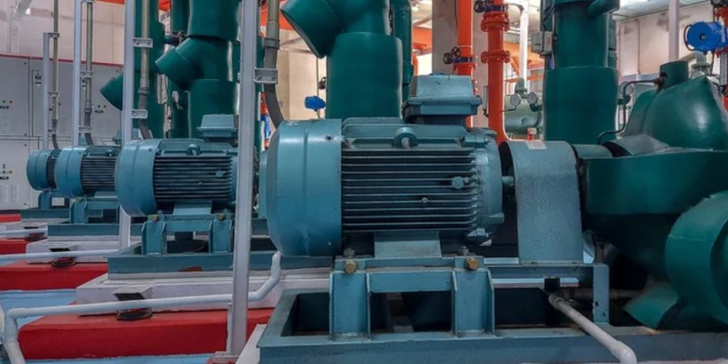 A row of large industrial motors is displayed in a mechanical room setting. 