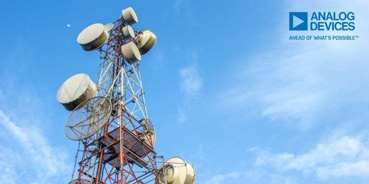 A tall telecommunication tower equipped with multiple satellite dishes and antennas, set against a clear blue sky. 