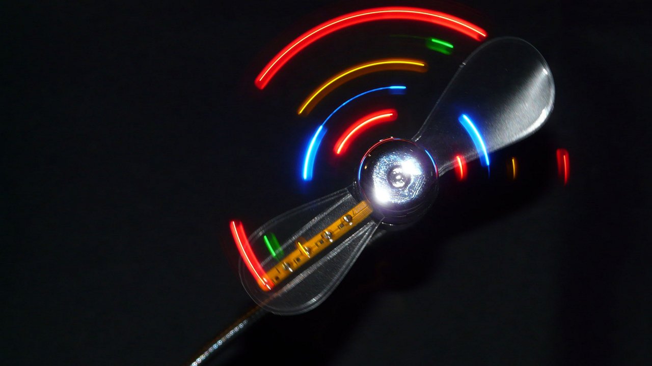 Spinning colorful LED propeller against a black background.