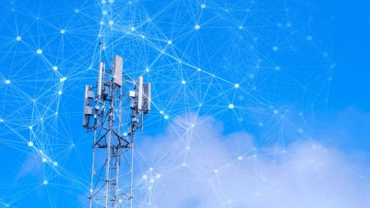 Una torre di telecomunicazioni si staglia contro un cielo azzurro brillante, dotata di molteplici antenne e ricevitori.