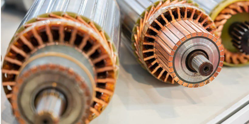 This image shows a detailed view of three electric motor rotors placed on a light-colored surface.