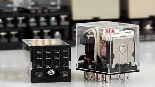 Deux relais électromécaniques transparents sont affichés sur une surface réfléchissante, l'un montrant le câblage interne et la bobine, l'autre montrant la configuration des broches.