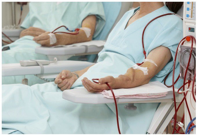 Two individuals are seated in a medical clinic receiving dialysis treatment