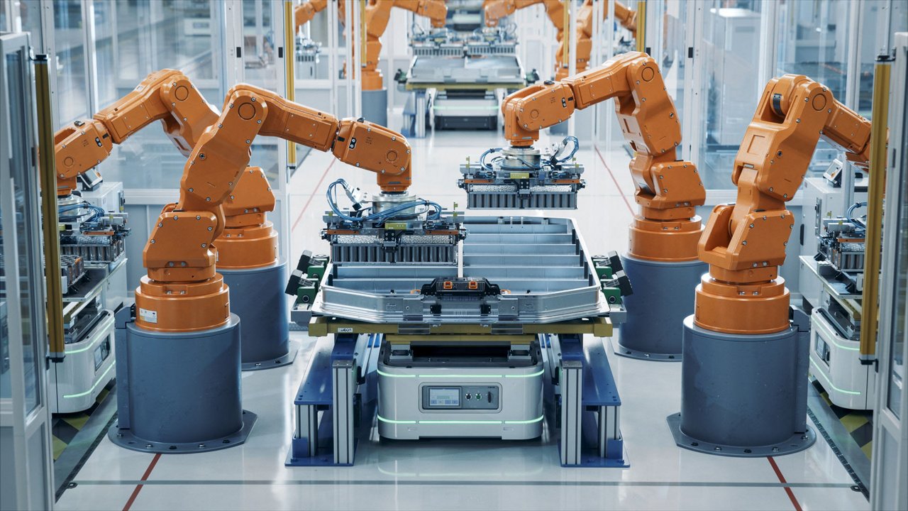 Modern Electric Car Automated Smart Factory. EV Battery Pack Production Line Equipped with Orange Advanced Robot Arms. Row of Robotic Arms inside Bright Plant Assemble Batteries for Automotive Industry