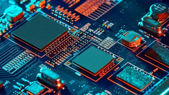 A detailed view of a circuit board featuring microchips and electronic components. The setting highlights intricate patterns and connections in a vibrant blue and orange palette. 