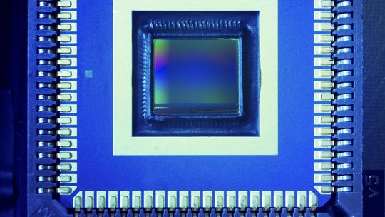 电子微芯片传感器的详细视图，展示复杂的电路结构和金属引脚。