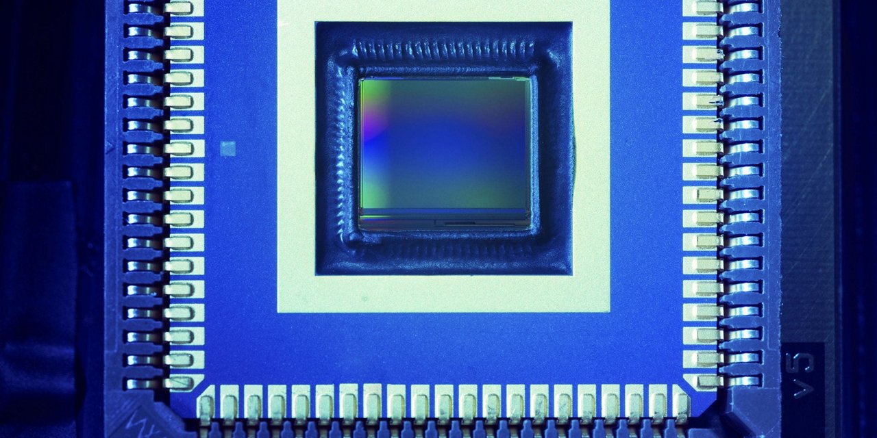 电子微芯片传感器的详细视图，展示了复杂的电路和金属引脚