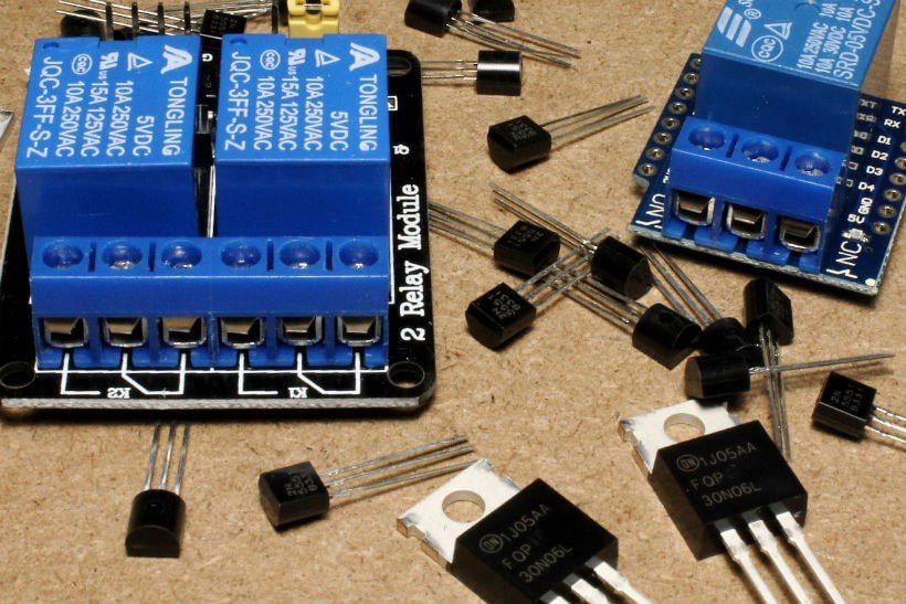 La imagen muestra dos módulos de relé azules etiquetados 'TONGING' y '2 Relay Module' junto a varios transistores y componentes electrónicos.