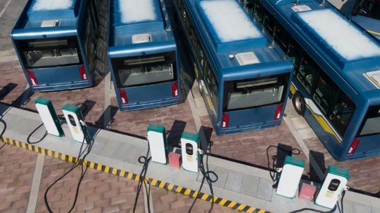 Una flota de autobuses eléctricos azules estacionados en una estación de carga