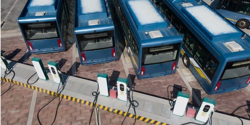 A fleet of blue electric buses parked at a charging station