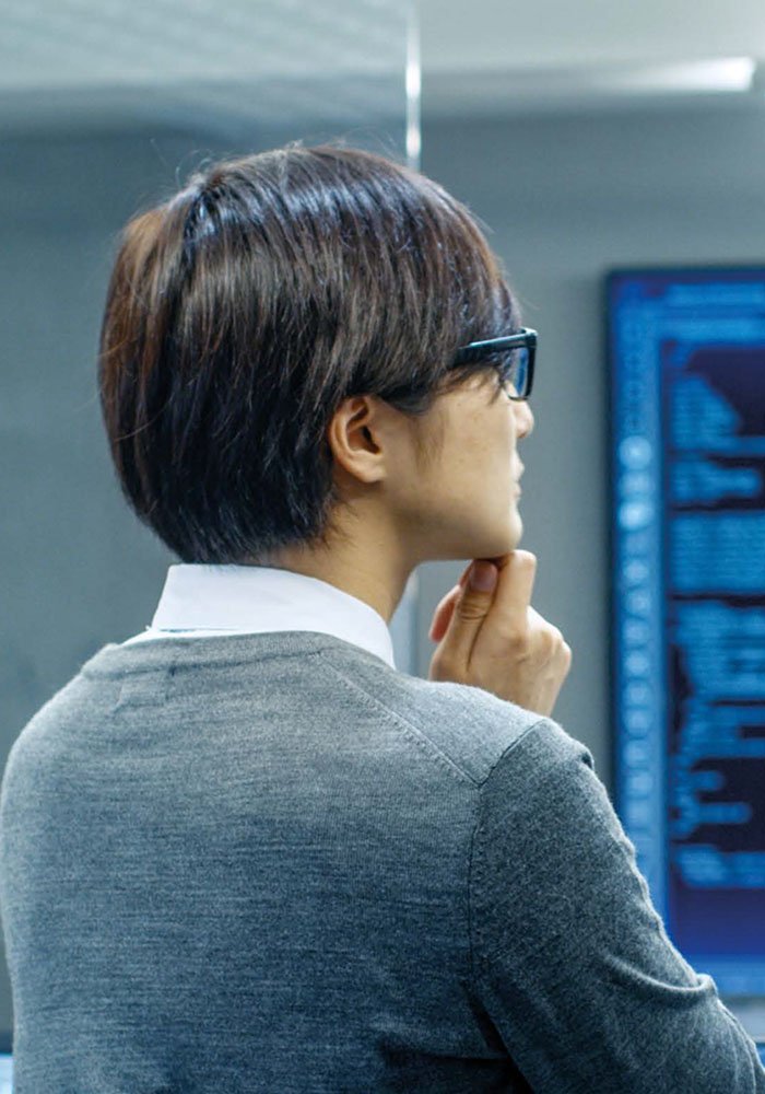 A person in a professional setting is seen analyzing data displayed on a large digital screen.