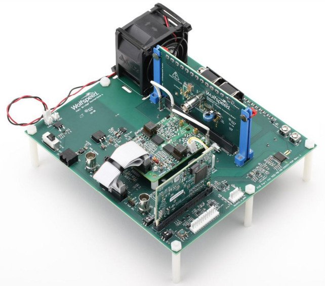 A detailed view of a WolfPack circuit board featuring multiple electronic components and a cooling fan. The setup includes connectors, chips, and wiring, mounted on a green PCB.